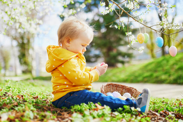 симпатичные маленькие одна летняя девочка играет яйцо охоты на пасху - child easter flower little girls стоковые фото и изображения