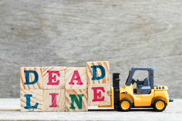 istock Toy forklift hold letter block d, e to complete word deadline on wood background 1136370322
