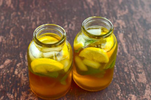Lemon iced tea with mint leaf in jars on wooden background