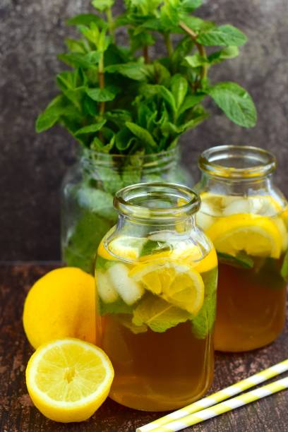 Lemon iced tea with mint leaf in jars on wooden background