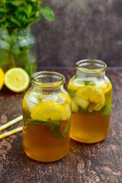 Lemon iced tea with mint leaf in jars on wooden background
