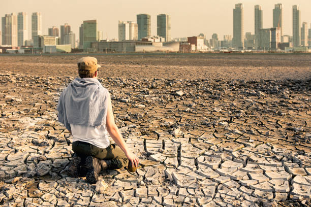 A man in the desert looks at the city after the effects of global warming Post-apocalyptic landscape. A man in the desert looks at the city after the effects of global warming drought stock pictures, royalty-free photos & images
