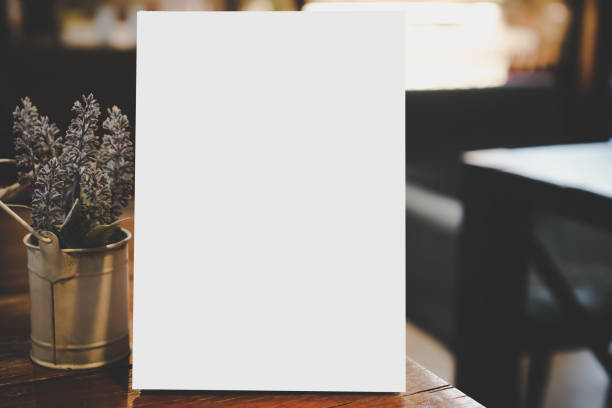 istock Mock up white Label for blank menu frame in restaurant cafe with plant pot. Stand booklet sheets paper tent card on table cafeteria display your product  background insert  text of customer. 1136375665