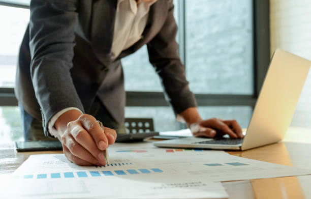 istock Businessman hand works on a laptop computer and uses a pen pointing at the graph. 1136377470