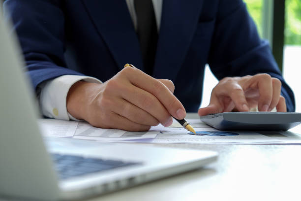istock Businessman hand works on a calculator and uses a pen pointing at the graph. 1136377471
