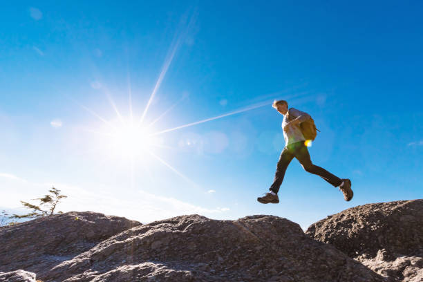 istock Man jumping over gap on mountain hike 1136383336