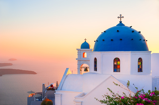 Church with blue dome at sunset on Santorini island, Greece. Summer landscape, sea view