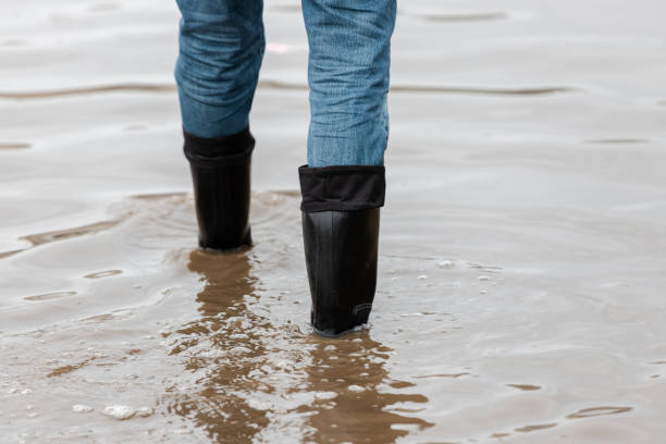istock A man in rubber boots walks through a muddy puddle 1136385443