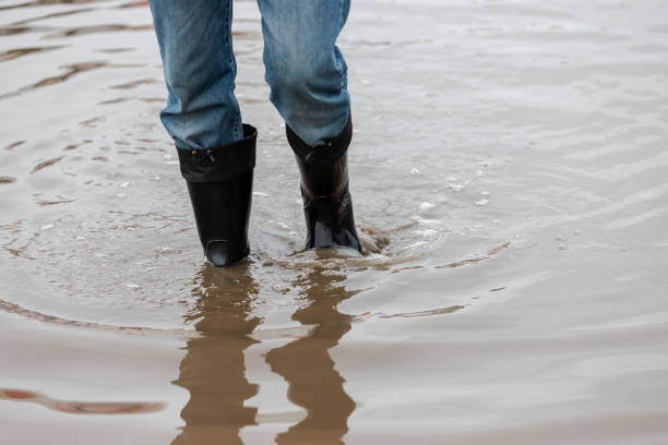 istock A man in rubber boots walks through a muddy puddle 1136385480