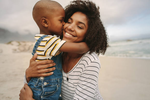 Boy enjoying at day out with his mother on the beach Son kissing his mother at the sea shore. Boy enjoying at day out with his mother on the beach. kissing photos stock pictures, royalty-free photos & images