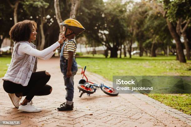Mother Helping Son Wearing Helmet For Cycling Stock Photo - Download Image Now - Child, Family, Mother