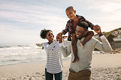 istock Parents carrying son on shoulders on beach vacation 1136387149