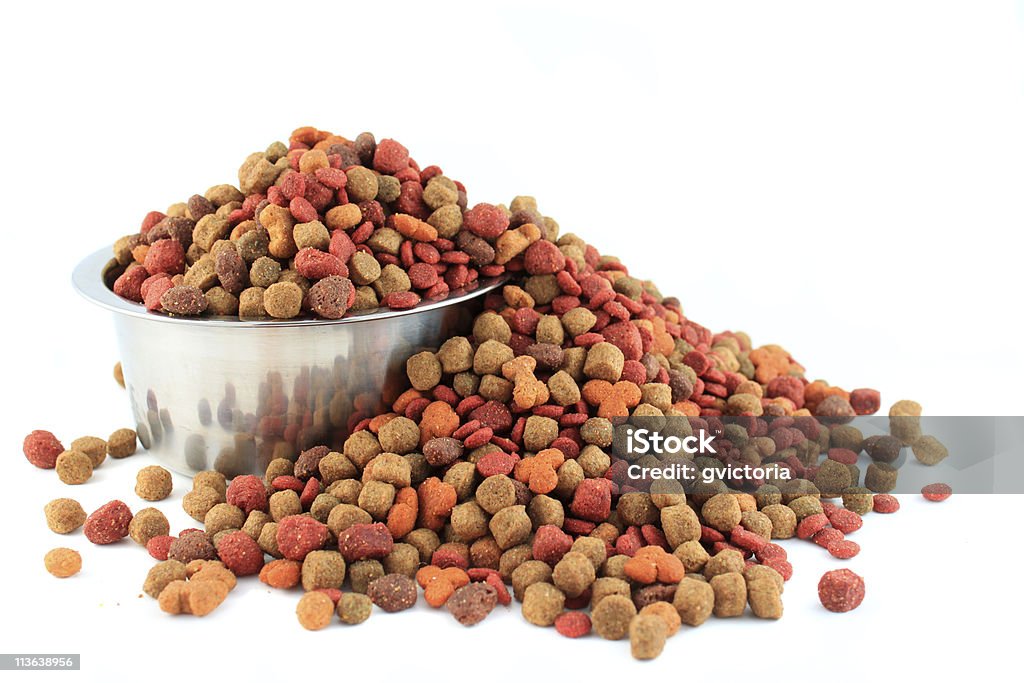 Bowl overflowing with dogfood Silver bowl full and overflowing with dog food bits on a white background Abundance Stock Photo