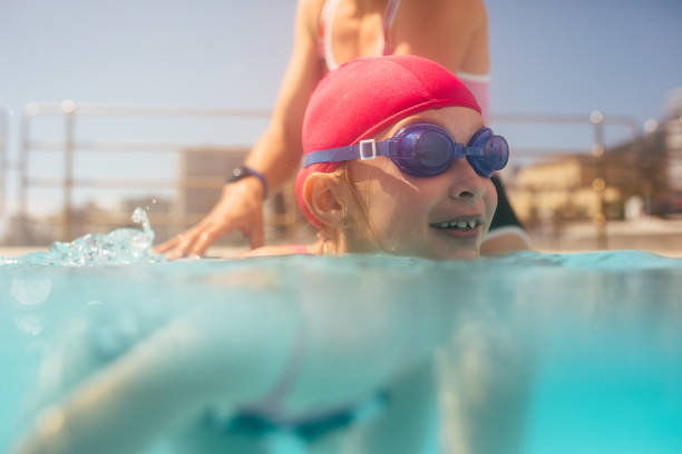 istock Cute girl learning to swim with coach 1136390539