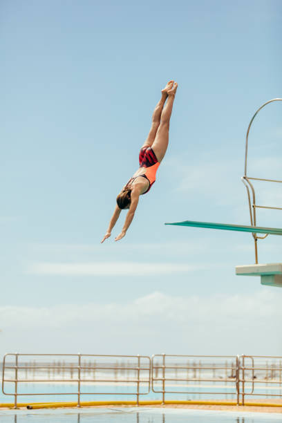 Diver diving in the pool Woman diving into the pool from spring board. Female diver diving upside down into the swimming pool. diving into water stock pictures, royalty-free photos & images