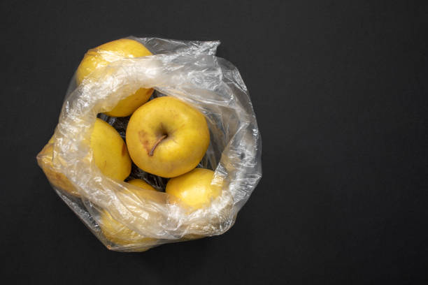 istock Yellow ripe apples in opened plastic bag on grey background. 1136392280