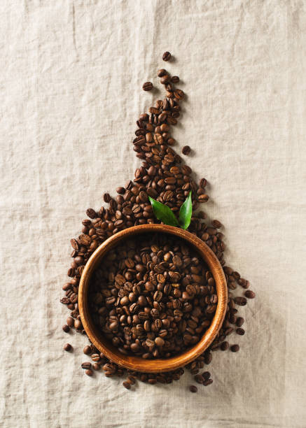 istock Coffee beans in bowl with leaf on table cloth grey texture 1136393910