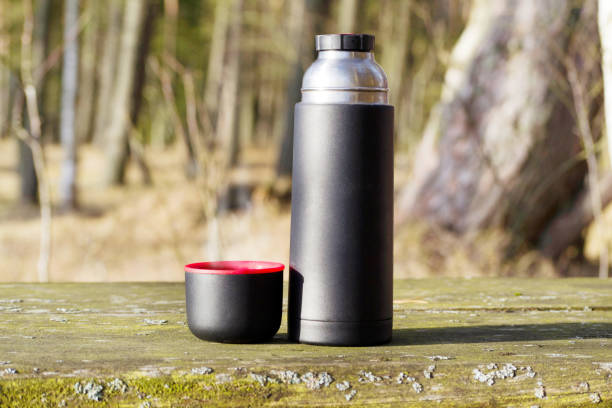 istock Thermos with hot tea on the old rustic table at the forest 1136397353