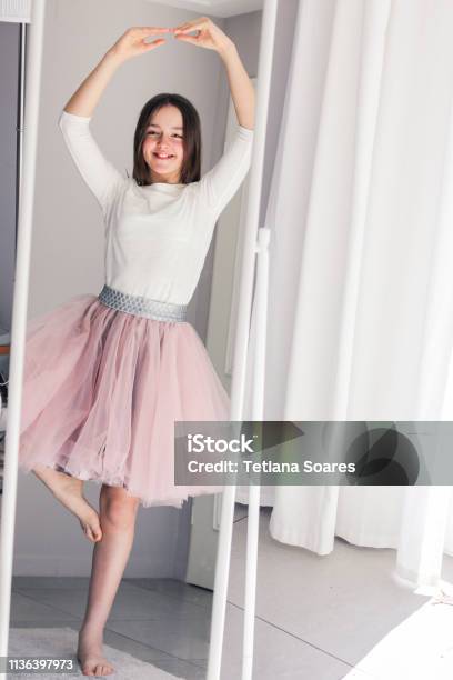 Pretty Happy Tween Girl Dancing Like Ballerina Looking At Mirror At Home Childhood Dreams Stock Photo - Download Image Now