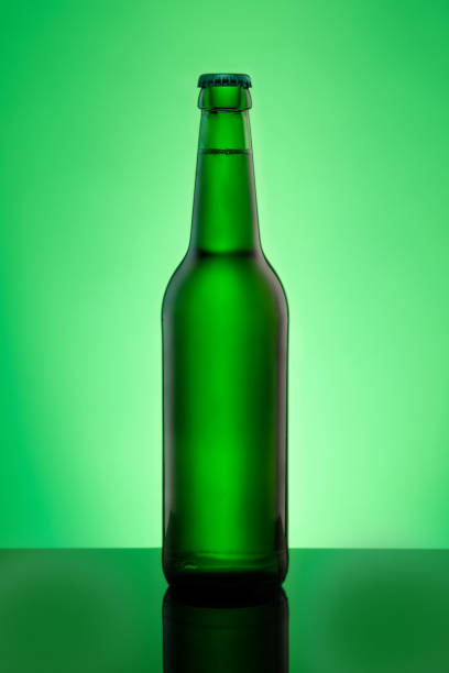 istock Green beer bottle with crown cap in vertical format in back lit close-up 1136398848
