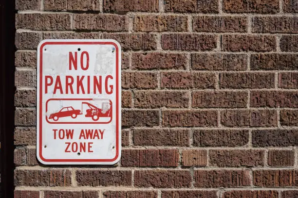 Photo of No Parking Sign on a Brick Wall. Tow away zone