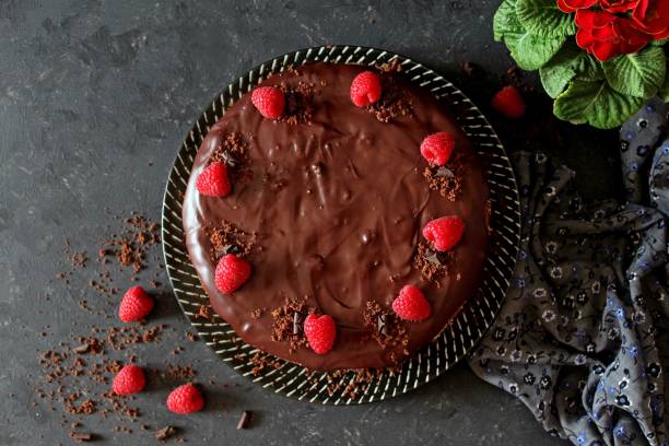Chocolate cake with fruits on a plate over dark background.