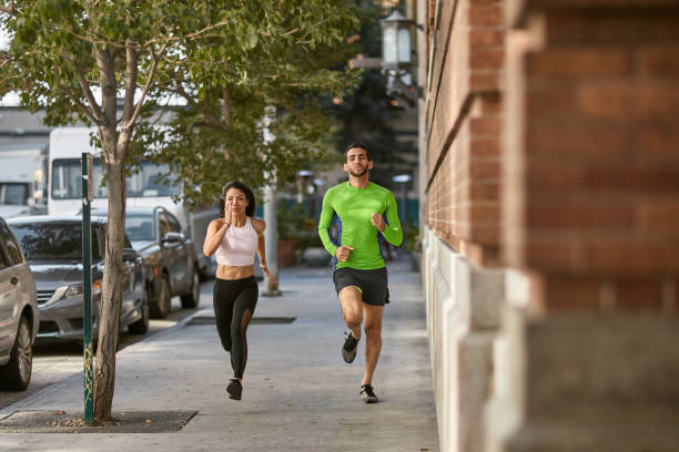 istock Determined friends jogging on sidewalk in city 1136404328