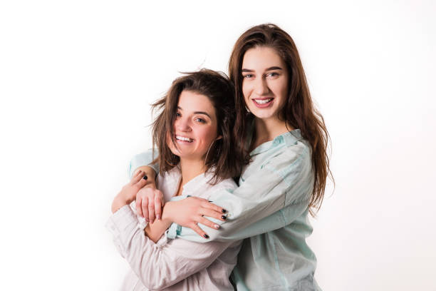 istock Two brunettes smile and embrace studio portrait 1136405438