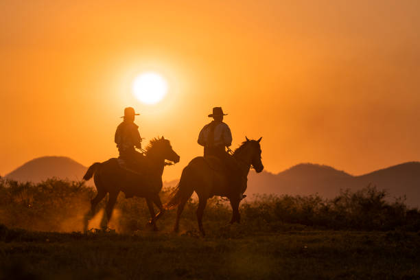 istock silhouette two cowboys ride with they horses under sunset 1136407954