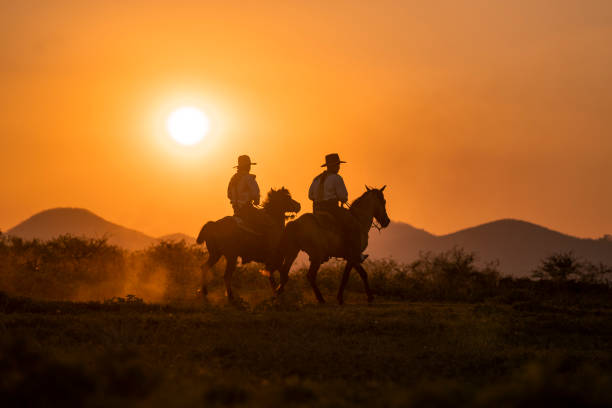 istock silhouette two cowboys ride with they horses under sunset 1136408018