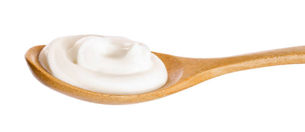 istock Sour cream in wooden spoon isolated on white background 1136408352