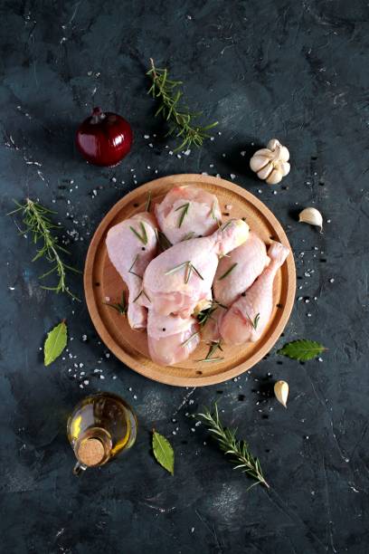 istock Raw uncooked chicken legs with ingredients for cooking, drumsticks on wooden board. 1136408459