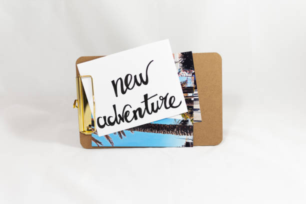 istock Clipboard with postcards and paper showing text new adventure 1136409581