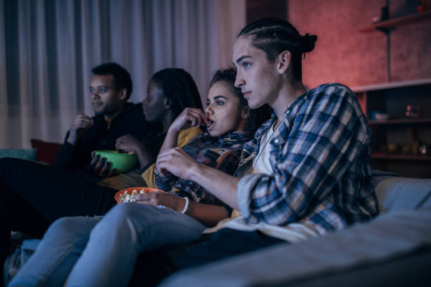 Friends watching TV Multi-ethnic friends watching TV together college dorm party stock pictures, royalty-free photos & images