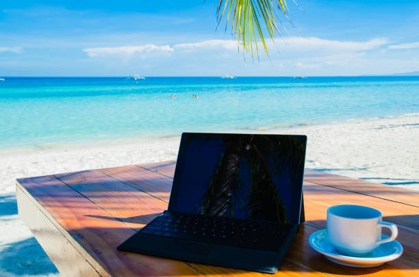 istock Laptop and coffee under palm tree on tropical beach 1136410284