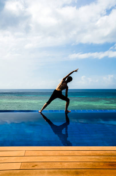 istock Young woman practicing yoga on the Infinity pool 1136410875