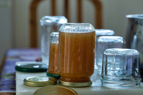 Many jars of jam aligned and placed on a table, some of the pots are filled with lemon jam and put upside down\nThe scene is photographed in a non-professional kitchen, in France on the French Riviera