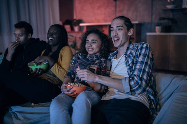 Multi-ethnic friends watching TV Multi-ethnic friends watching TV together college dorm party stock pictures, royalty-free photos & images