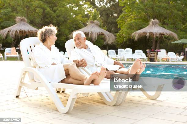 Couple Holding Hands While Resting On Deck Chairs Stock Photo - Download Image Now - 60-64 Years, 70-79 Years, Active Lifestyle