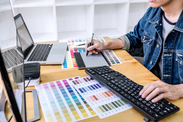 istock Image of male creative graphic designer working on color selection and drawing on graphics tablet at workplace with work tools and accessories in workspace 1136413114
