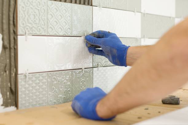 instalando telhas cerâmicas na parede na cozinha. colocando espaçadores de azulejos com as mãos, renovação, reparação, construção. - ceramics tile ceramic wall - fotografias e filmes do acervo