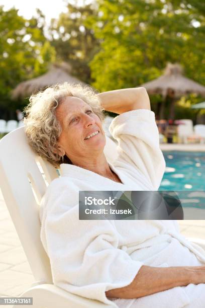 Thoughtful Senior Woman Resting On Deck Chair Stock Photo - Download Image Now - Senior Women, Swimming Pool, 60-64 Years