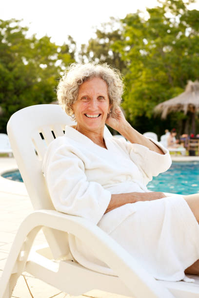 istock Senior woman resting on deck chair at poolside 1136413229