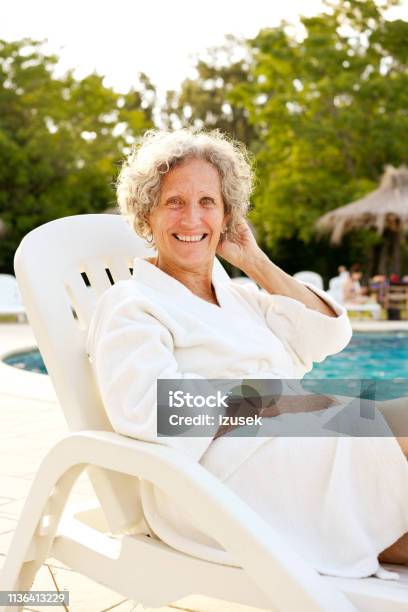 Senior Woman Resting On Deck Chair At Poolside Stock Photo - Download Image Now - 60-64 Years, Active Lifestyle, Active Seniors