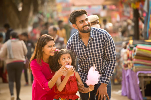 Indian family at street market Joyful Indian family with cotton candy at street market happy indian young family couple stock pictures, royalty-free photos & images