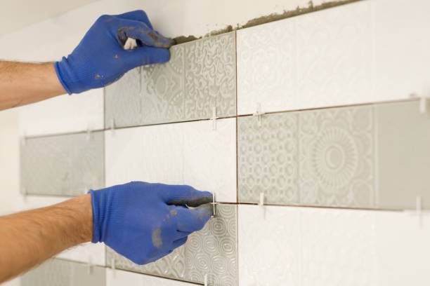 istock Installing ceramic tiles on the wall in kitchen. Placing tile spacers with hands, renovation, repair, construction 1136413418