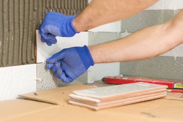 istock Installing ceramic tiles on the wall in kitchen. Placing tile spacers with hands, renovation, repair, construction. 1136413455