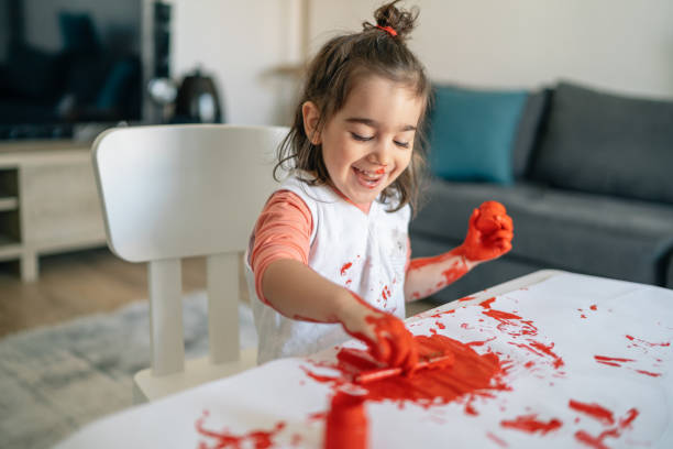 niño feliz divirtiéndose haciendo la pintura del dedo en casa - paintings child house childhood fotografías e imágenes de stock
