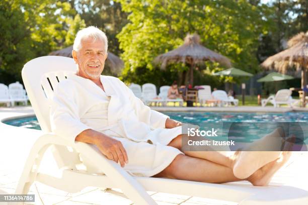 Portrait Of Senior Man On Deck Chair At Poolside Stock Photo - Download Image Now - Deck Chair, Only Men, Senior Adult