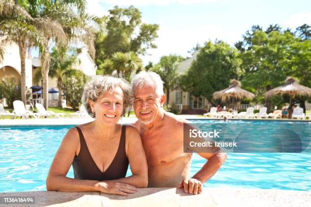 Portrait Of Smiling Senior Couple In Summer Stock Photo - Download Image Now - Senior Couple, Swimming Pool, Latin American and Hispanic Ethnicity